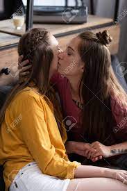 Two Lesbians Kissing And Holding Hands While Sitting On Sofa In Living Room  Stock Photo, Picture and Royalty Free Image. Image 130227167.