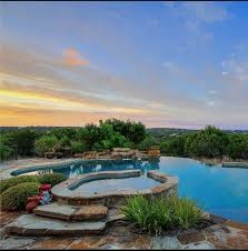 Texas Hill Country Boasts This Beautiful Freeform Pool And Spa With A Negative Edge Grotto And Flagstone Decking Country Pool Pool Houses Backyard Pool