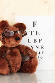 Teddy Bear With Glasses On Eyesight Test Chart Background Close Up