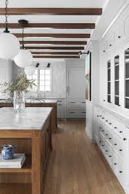 It acts as a arch amid… Remodeling Kitchen Wood Floors Exposed Beams White Cabinets Marble Countertops Lakeside Development