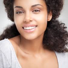 Pretty young female standing at the beach with group of friends in background. How Gum Grafting And Lifts Can Change Your Smile Torbram Dental Blog
