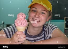 High school girl scooping up ice cream for a customer Stock Photo