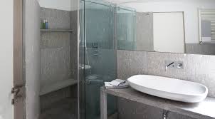 Ispirazione per un'in muratura stanza da bagno con doccia minimal con ante lisce, ante in legno bruno, doccia ad angolo, wc sospeso, piastrelle beige, pareti bianche, lavabo a bacinella, pavimento beige e porta doccia. Un Tocco Di Eleganza Con Il Bagno In Muratura