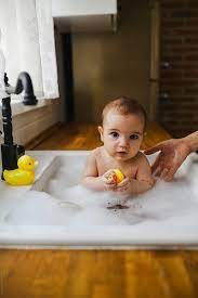 Bathing your baby will involve using one arm to hold your baby securely whenever they are in water. Baby Having A Bath In The Kitchen Sink By Dejan Ristovski