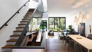 An image of a modern house with slated roof and a garden laid to lawn and overlooking the sea. Modern Suburban Home With A Mirrored Staircase Digsdigs