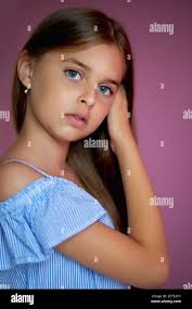 portrait d'une fille modèle caucasienne sérieuse posant à l'appareil photo  isolé sur fond rose. jeune adolescent en robe d'été regarder l'appareil  photo Photo Stock