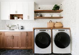 In a kitchen beside a stainless steel refrigerator, a stacked white front loading washer and dryer is enclosed behind a white door adorning a polished nickel handle. 20 Drop Dead Gorgeous Waterfall Countertops