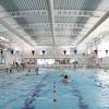 An outdoor community swimming pool, the complex looks tattered with its tarnished lifeguard stands and stinky toilets. 1