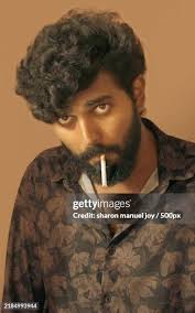 Portrait Of Young Man Smoking Cigarette Against Wall High-Res Stock Photo