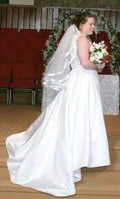The mermaid skirt sculpts and softly streams into a glistening train. David S Bridal White Michaelangelo Wedding Dress With Gem