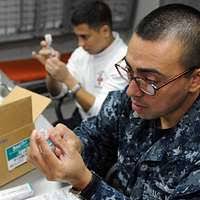 Hospital Corpsman 1st Class Samuel Karr administers a smallpox vaccine to  Gunner's Mate Seaman Brandon Tokarski during a ship-wide mass smallpox  inoculation.