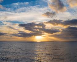 A brilliant dramatic autumn sunrise, with warm orange sun rays shining through clouds and. Sun Shining Through Some Clouds Prior To Sunset At Sea Photograph By William Dickman