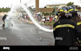 Chocolay Township firefighters Tom Kidd, right, and George Meister aim the  nozzle at teammates John Verran and Brad Johnson as they attempt to fill a  barrel up with water during the annul