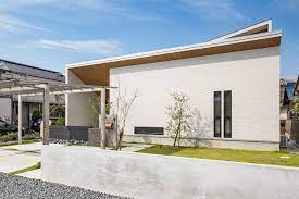 白のタイルと木目を使用したナチュラルな外観デザイン 玄関ポーチに採用した勾配軒天によって 木目のアクセントを強調し 印象的なファサードに モダンハウスデザイン 住宅 外観 家 外観 おしゃれ 平屋