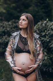 Mujer embarazada en un impermeable en el parque | Foto Premium