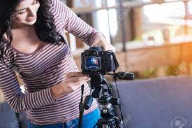 Amateur Video. Delighted Nice Positive Woman Holding A Camera And Putting  It On A Tripod While Preparing To Record A Video Stock Photo, Picture And  Royalty Free Image. Image 92668329.