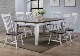 A great room with a dining area featuring a gray dining table and white chairs on a gray rug, surrounded by white walls and ceiling. Riley White Dining Room Table 7 Pc Set Evansville Overstock Warehouse
