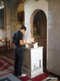 Image Young Coptic Man Praying صورة شاب يصلي و يوقد الشموع في كنيسة قبطية