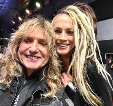 The photo shows the smiling lead vocalist of the hard rock band  Whitesnake🐉, Mr. David Coverdale with the smiling Irish bassist, Mrs.  Tanya O'Callaghan. Mrs. Tanya O'Callaghan joined in the band Whitesnake🐉in