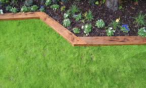 Surrounding the walkway is a bed of bark with plants and rocks interspersed to create a cohesive garden design. How To Create Wooden Garden Borders