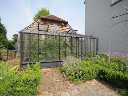 What do you need to build a walipini greenhouse? Wall Greenhouse In Wrought Iron Leaning Against Annex In Garden