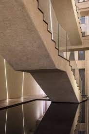 A Dark Pool At The Base Of The Stairs Reflects The Surfaces Of Walls And Ceilings Pierced By Glowing Lines Of Inset Lighting Concrete Staircase Stairs Architecture