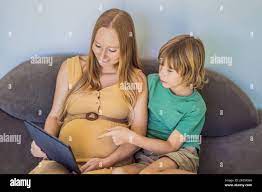 pregnant mom and son look at the tablet. Reading a book or watching a  cartoon or making a video call. Look at the photo from the ultrasound Stock  Photo - Alamy