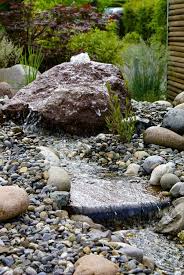 Bachlauf Im Garten Ausgehend Von Einem Quellstein Fliesst Das Wasser Dem Kiesbett Entlang Salamander Naturgar Bachlauf Im Garten Quellstein Wasser Im Garten