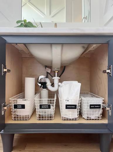 Under sink cabinet showing sink bowl plumbing and organised cleaning products
