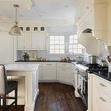 To complement the black handle bars, a white kitchen island with black granite countertop is added. Ivory Kitchen Cabinets Design Ideas