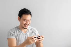 Smile and happy face of Asian man play mobile game. - Stock Image -  Everypixel