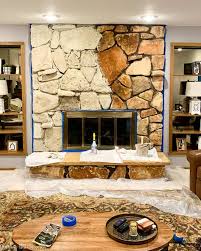 With manufactured veneer stone running from the hearth, up the chimney, and culminating at the ceiling, this stylish fireplace from evolution of style now has a more natural look that befits the home's friendly, organic style. Limewash Stone Fireplace Makeover Bye Bye Orange Stone Fireplace Hello Neutral Stone Beauty Average But Inspired