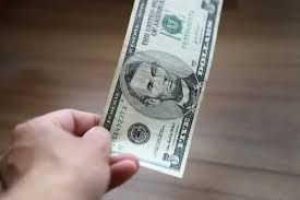 Person paying for a purchase with a 5 US dollar bill. Hand holding a bill  to pay in cash. Customer paying a purchase. Money in hand.