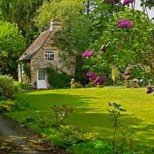 A Cottage Surrounded By Flowers And Warmth Stone Cottage English Cottage Storybook Cottage