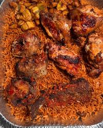 Plate of jollof rice served with fried chicken pieces on a white background