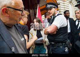 London, UK. 1st August 2019. Ian Bone of Class War questions police about  their actions as IWGB Cleaners and Facilities Branch picket and protest at  exclusive Mayfair private club LouLou's for kitchen