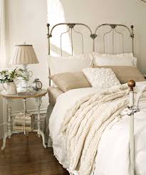 Traditional touches still include layered and textured bedding, a rustic wood ceiling, the wrought iron and crystal chandelier, a tufted leather bench, and a vintage mirror above the upholstered headboard. Wrought Iron Bedside Table Ideas On Foter