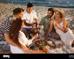 group enjoying a picnic on a sandy beachの画像