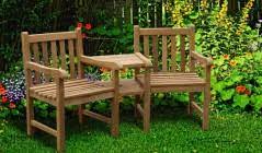 Elder couple smiling and relaxing seated in the garden. Teak Companion Seats Garden Love Chairs Wooden Love Seats Corido