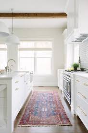 Red And Blue Kilim Rug Covers Wood Floors Framing A White Kitchen Island Fitted With A Farmhouse Sink Acc Home Kitchens Kitchen Remodel