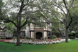The Front Yard Of This Dallas Tudor Style House Has A Large Tree A Bright Green Grass Lawn And A Row Of Pink Calad Tudor House Curb Appeal Front Door Entrance