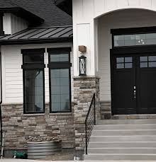 Black And White House With Wood Garage Door Modern Rustic White Farmhouse Black Doors Black Trim Stone Board And Baton Modern Farmhouse Exterior White Exterior Houses Exterior Paint Colors For House