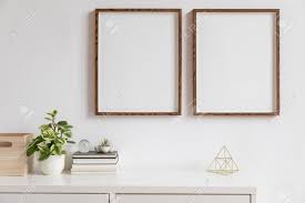 Maybe you would like to learn more about one of these? Stylish White Home Decor Of Interior With Two Brown Wooden Mock Up Photo Frames With Books Beautiful Plant In Stylish Pot Gold Pyramid And Home Accessories Minimalistic Scandinavian Room Stock Photo Picture