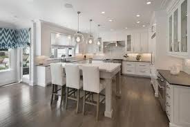Modern white kitchen with knobless cabinets and a peninsula with wood surface attached to a white table island with mirror legs and a pair of stylish cube stools on. Kitchen Island With Bar Stools You Ll Love In 2021 Visualhunt