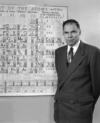 glenn seaborg standing by periodic chart of the atoms