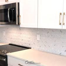 The herringbone backsplash combines white, gray, and yellow tiles to create a stunning graphic pattern. Archery White Oak Herringbone Mosaic Glass Tile