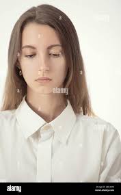 sad young woman in white blouse looks down on white background Stock Photo  - Alamy