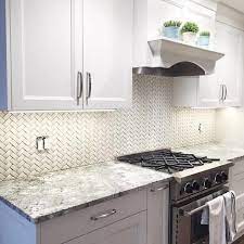 Glossy white glazed herringbone backsplash tiles in a contemporary kitchen complements white shaker cabinets with oil rubbed bronze hardware and white quartz counters. 1001 Ideas For Stylish Subway Tile Kitchen Backsplash Designs