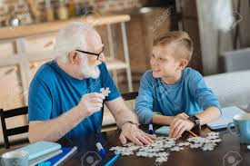 The key is to find a puzzle that suits their ability level and has a picture they like. Entertaining Activity Joyful Nice Pleasant Elderly Man Sitting At The Table And Collecting Jigsaw Puzzles While Looking At His Grandson Stock Photo Picture And Royalty Free Image Image 91282560