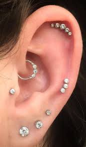 an amber stud a pearl stud and a gold hoop in the daith make up a bold and creative setup in 2021 different ear piercings ear piercings chart types of ear piercings